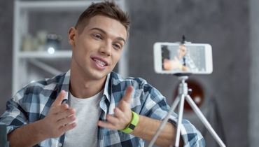 Junger Mann filmt sich selbst mit mit seinem Smartphone